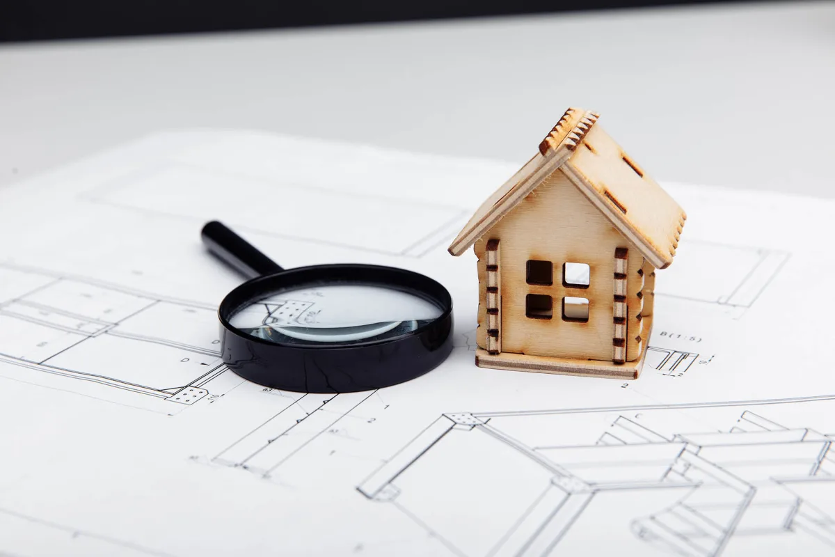 Mini model of house and a magnifying glass on a drawing. Real estate building concept.